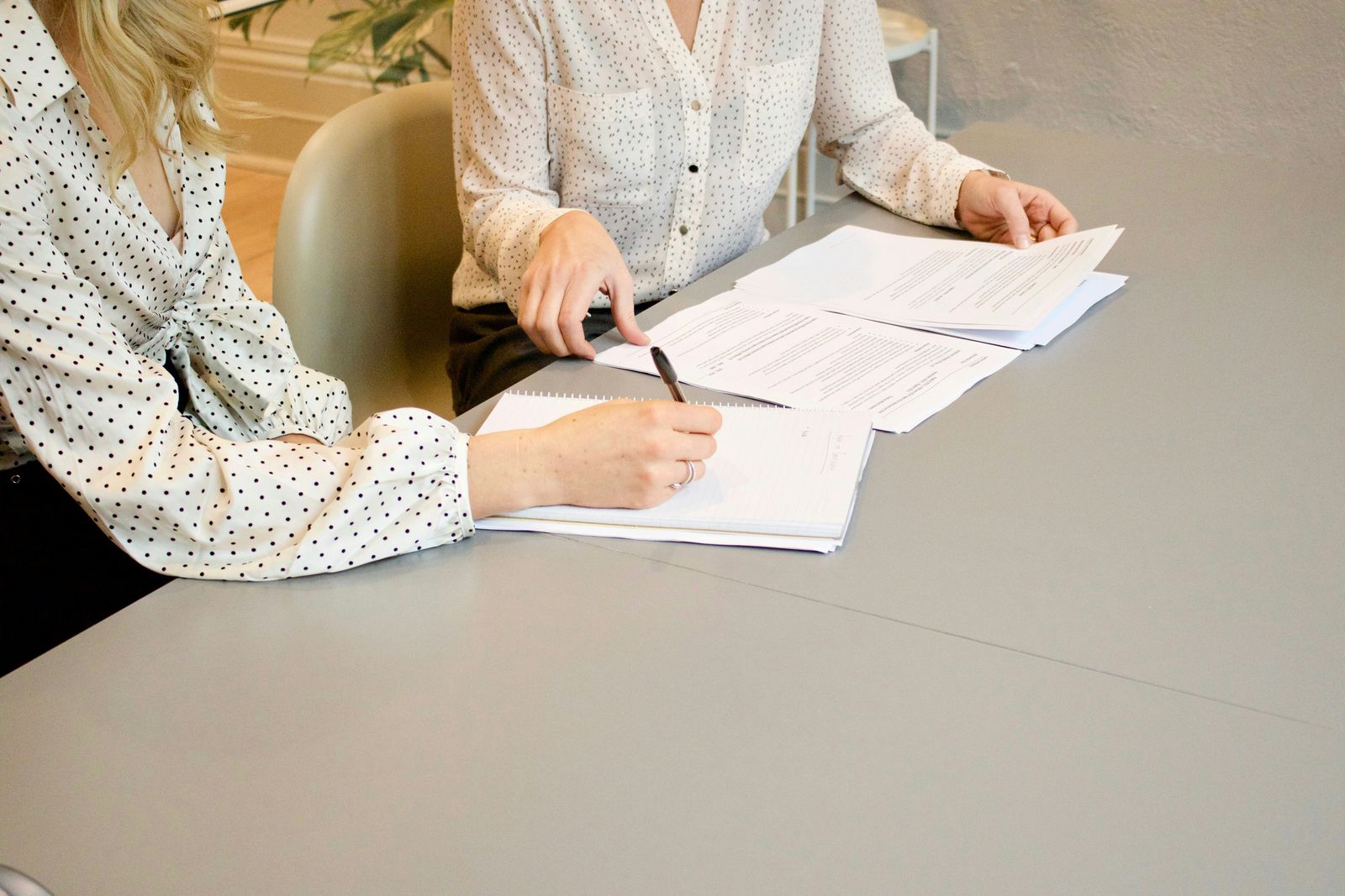 Two people sitting at a table reviewing and signing paperwork together.