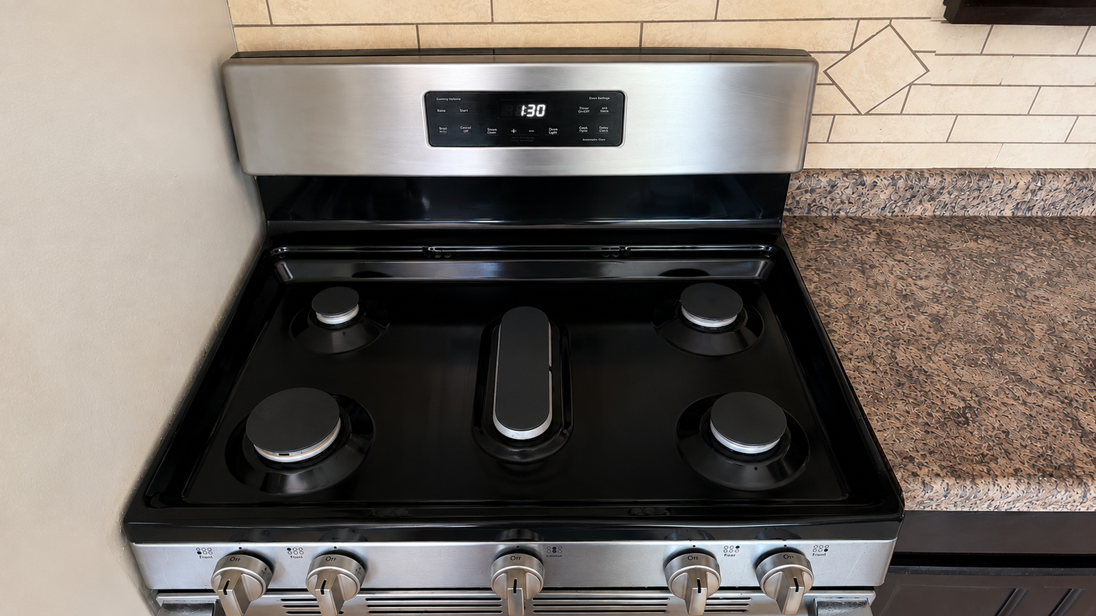The same gas stove after cleaning, with burners, grates and surface gleaming.