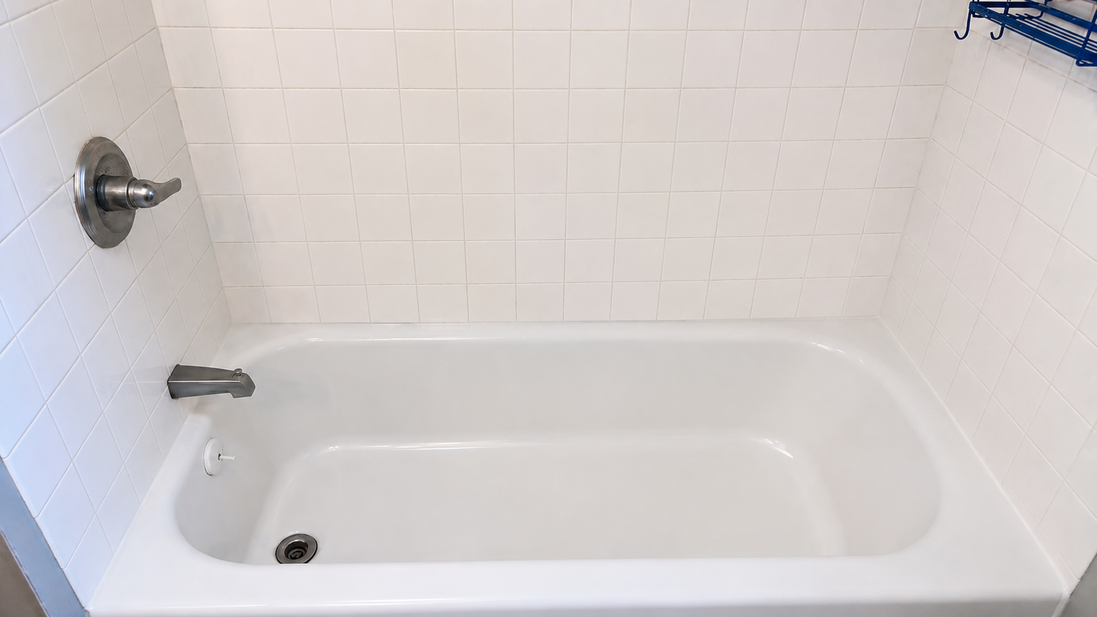 The same bathtub and tile wall cleaned back to bright white.