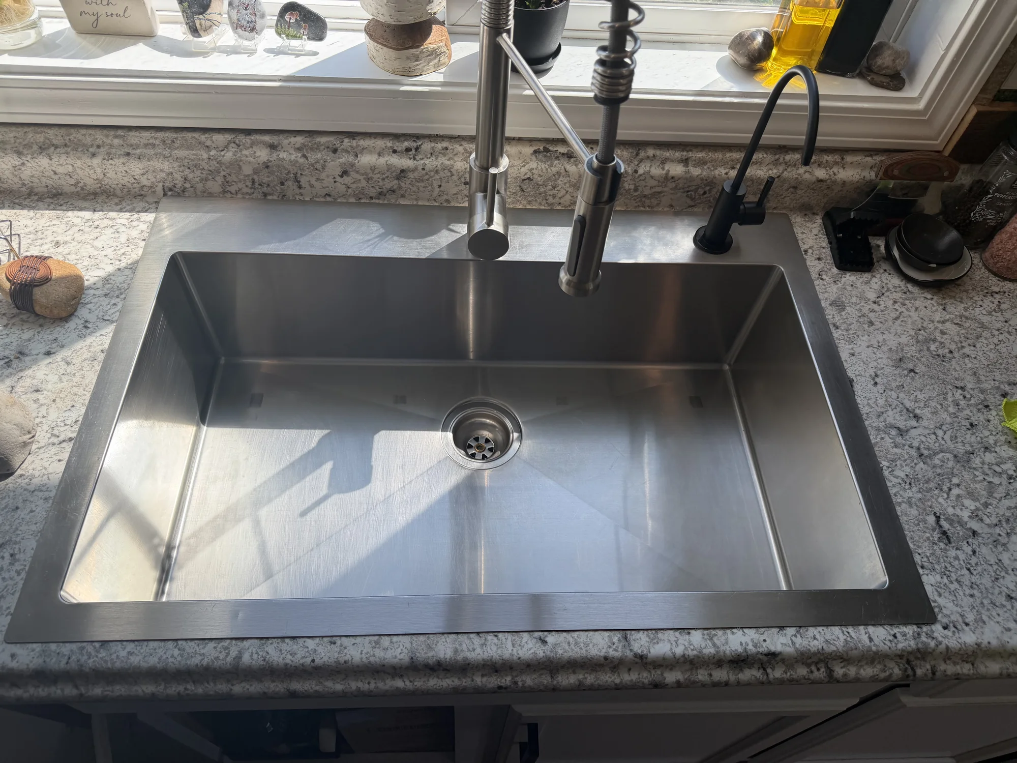 The same kitchen sink after cleaning, gleaming and free of spots or residue.