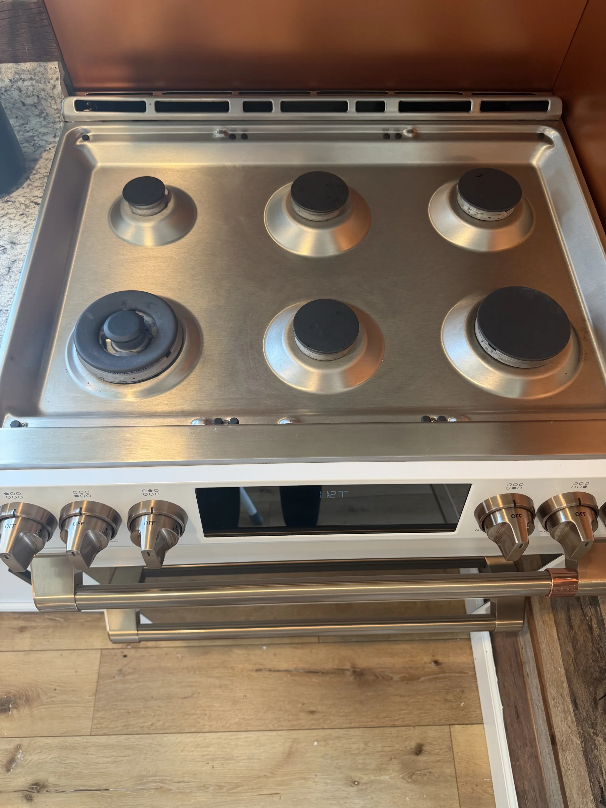The same six-burner gas stove top after cleaning, with a bright, streak-free stainless finish.
