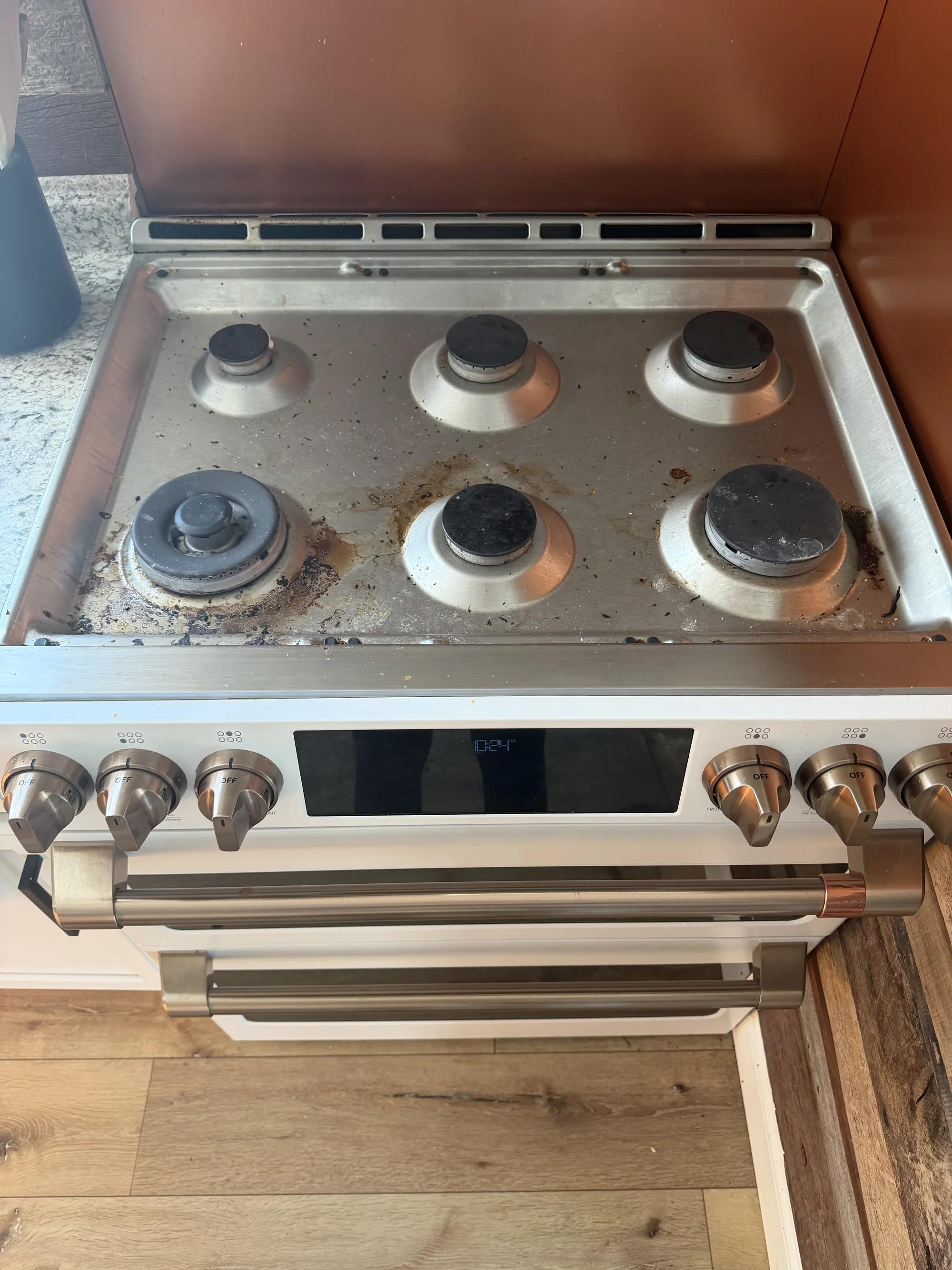 A stainless steel six-burner gas stove top with heavy grease and grime buildup around the burners.